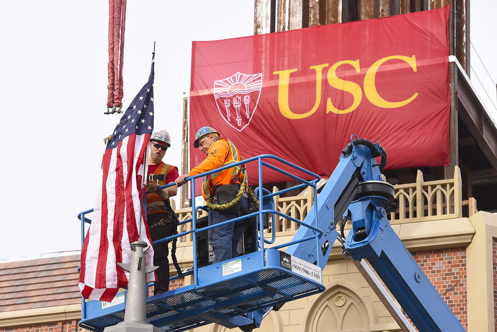 Construction workers mount an American flag to the spire during the topping out ceremony marking the halfway point of construction on USC Village. (USC Photo/Gus Ruelas)